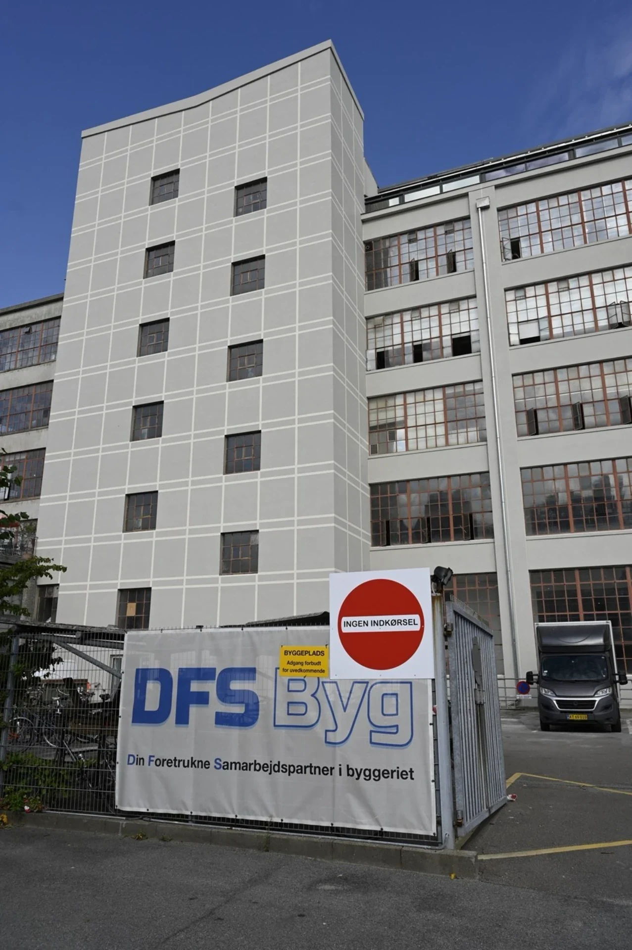 Moderne bygning under opførelse med DFS Byg logo i København.