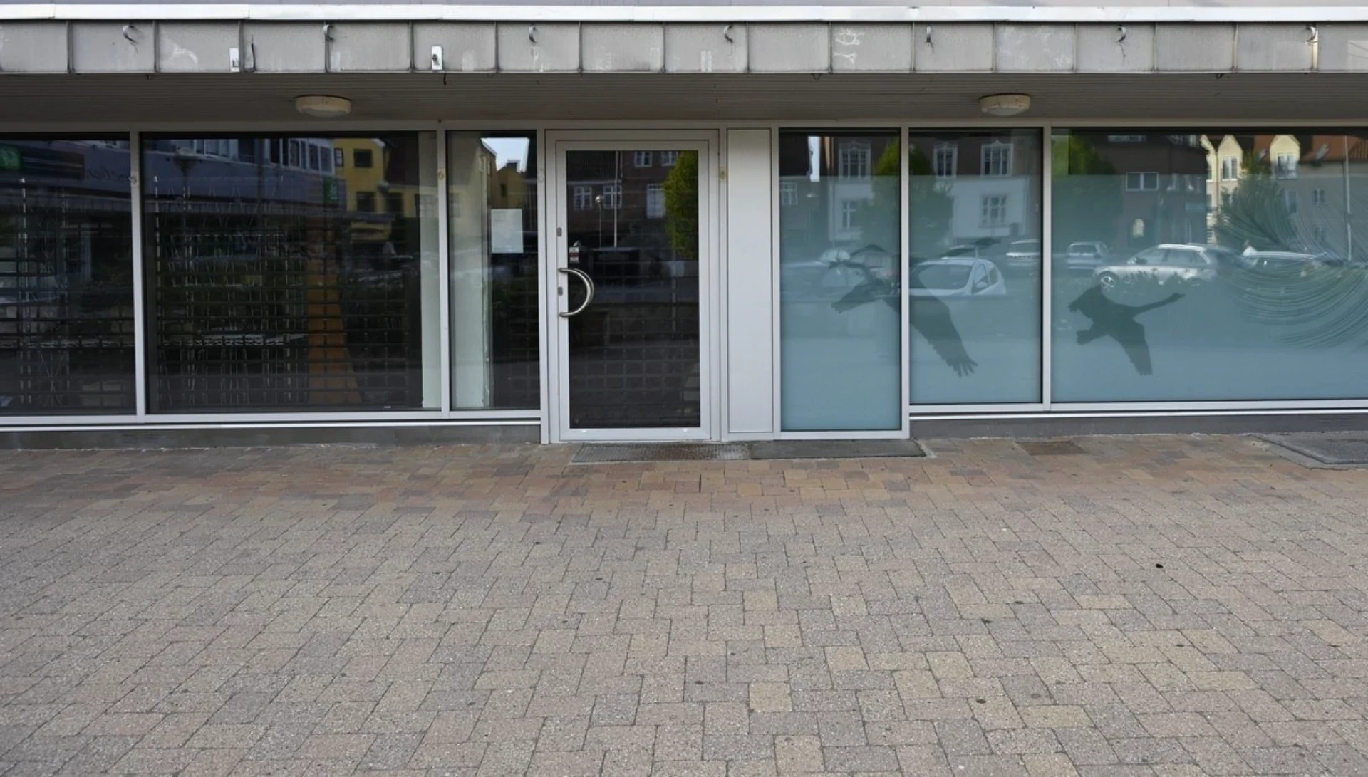 Kontorbygning med glasfacade og indgangsdør i centrum.