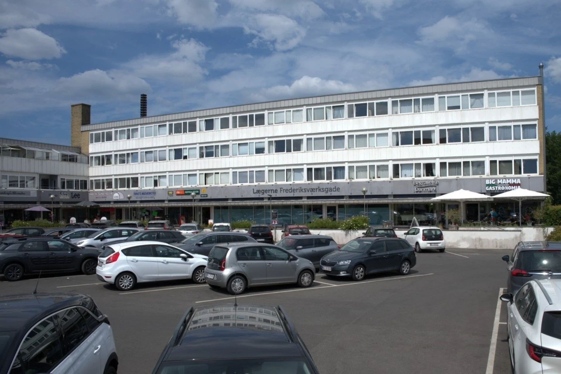 Kontorbygning i Frederiksværksgade med parkeringsplads foran.