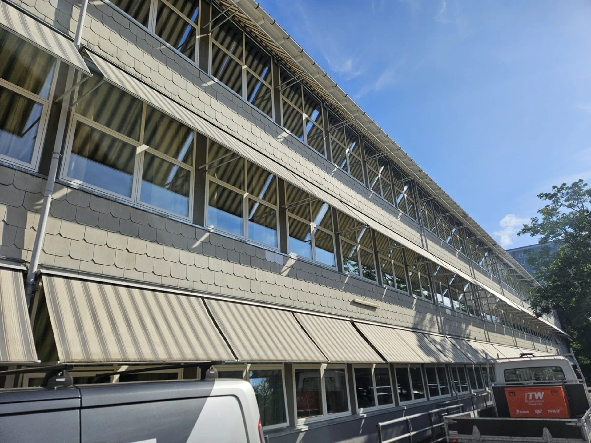 DFS Byg ApS - Moderne kontorbygning med store vinduer og udendørs terrasse.