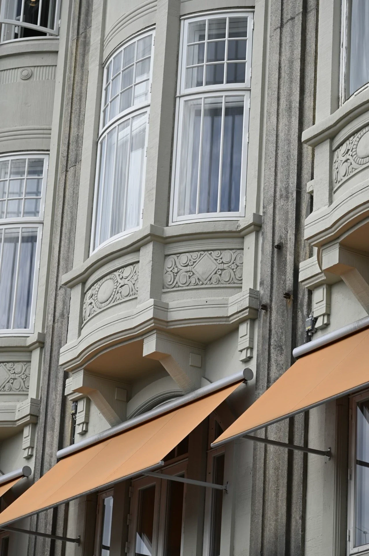 Højtalende facade med store vinduer og dekorative detaljer.