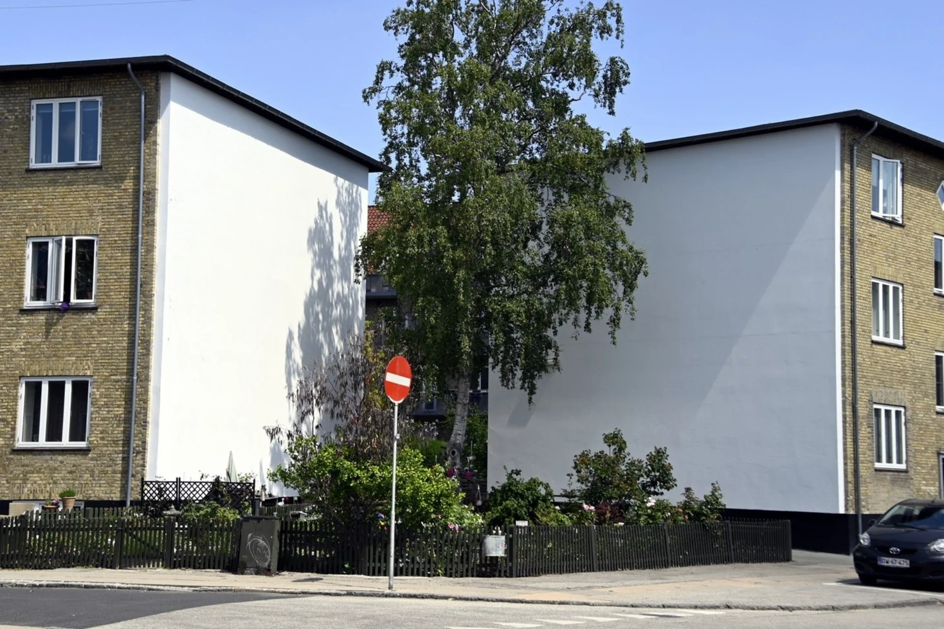 To boligblokke med hvide facader og grønne områder i København.