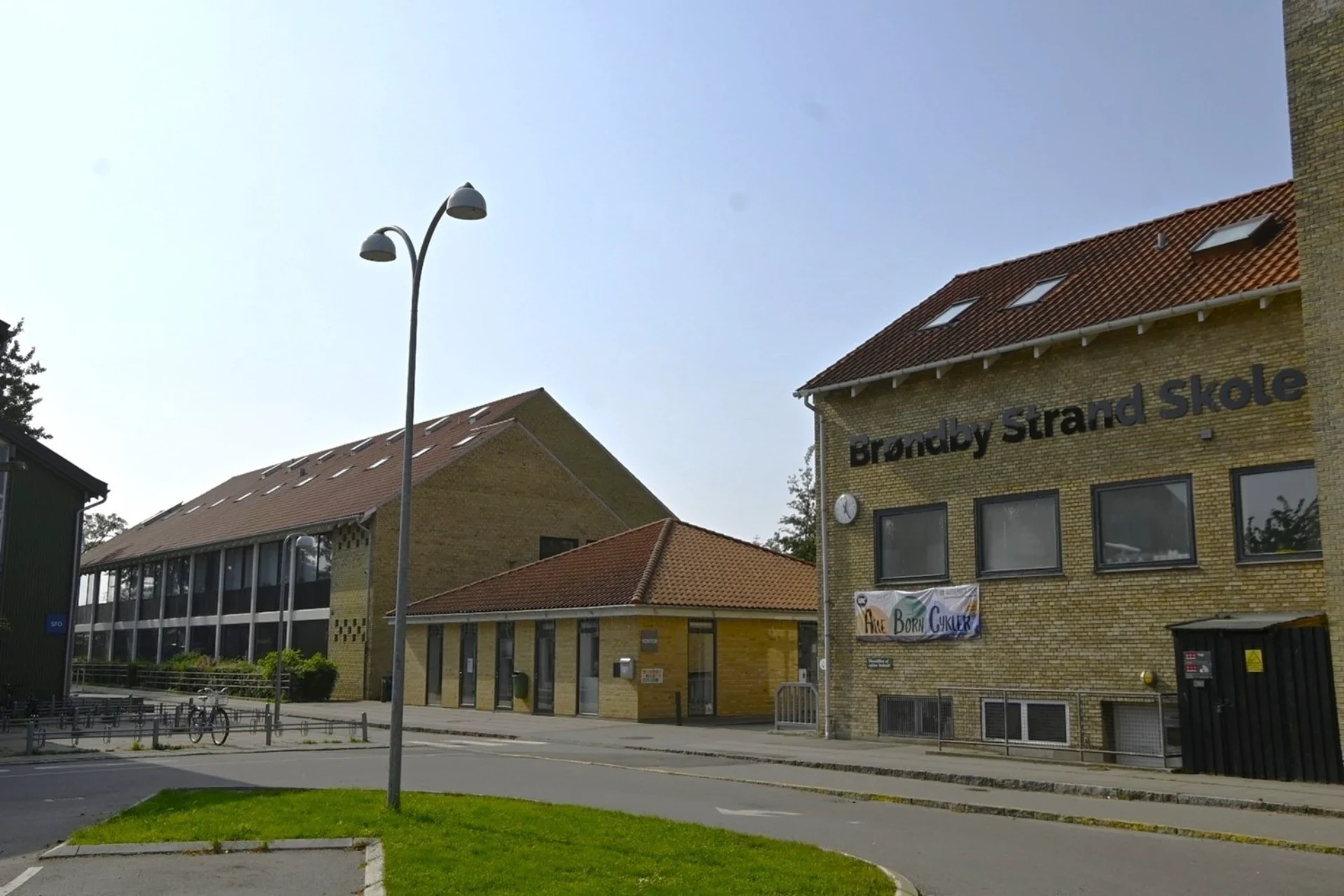 Brøndby Strand Skole, en moderne skolebygning med gule mursten og store vinduer, er et centralt udda.