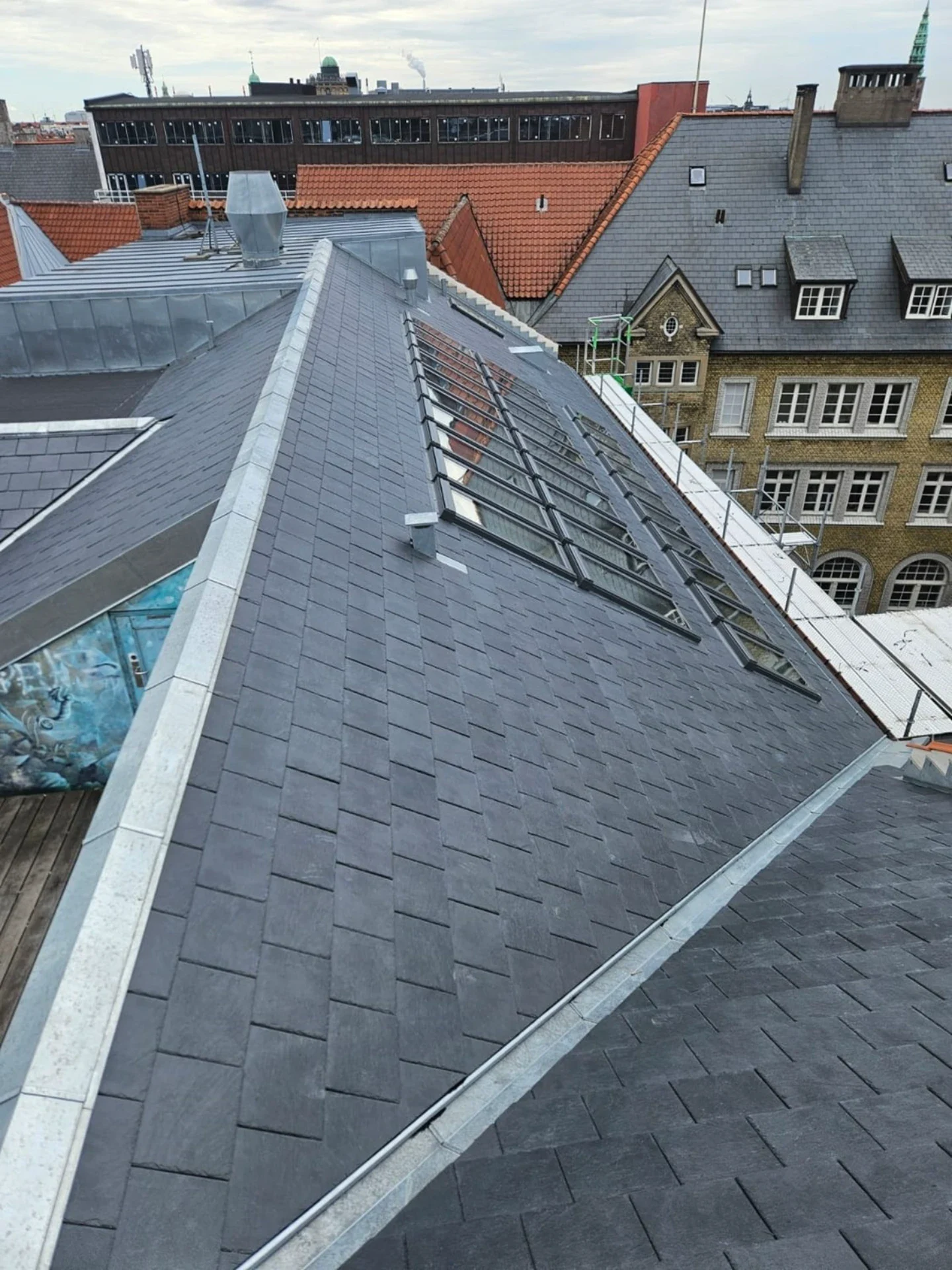 Billede af et nyt tag med solpaneler og tagrender i København.
