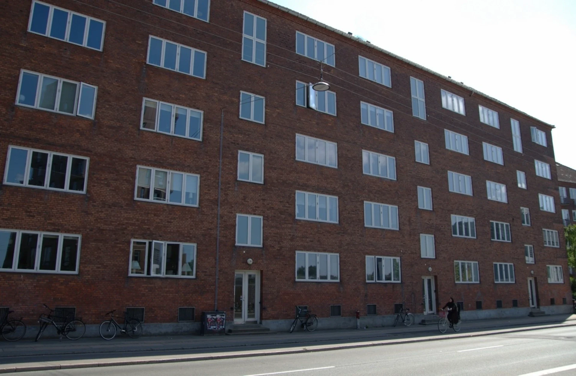 Husfacade med mange vinduer i rødt murværk.