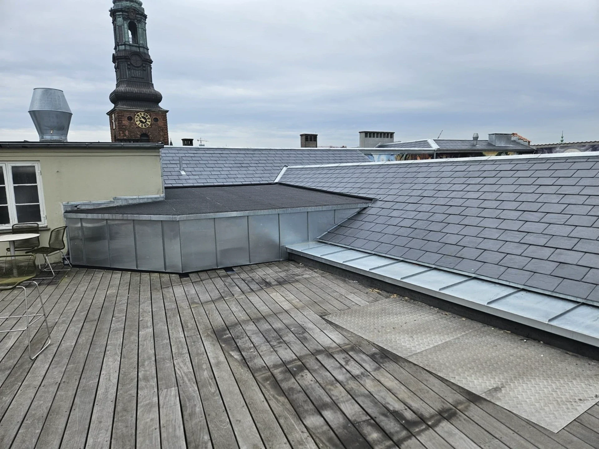 Tagterrasse med tagrender og byudsigt, moderne tagkonstruktion og bymiljø i baggrunden.