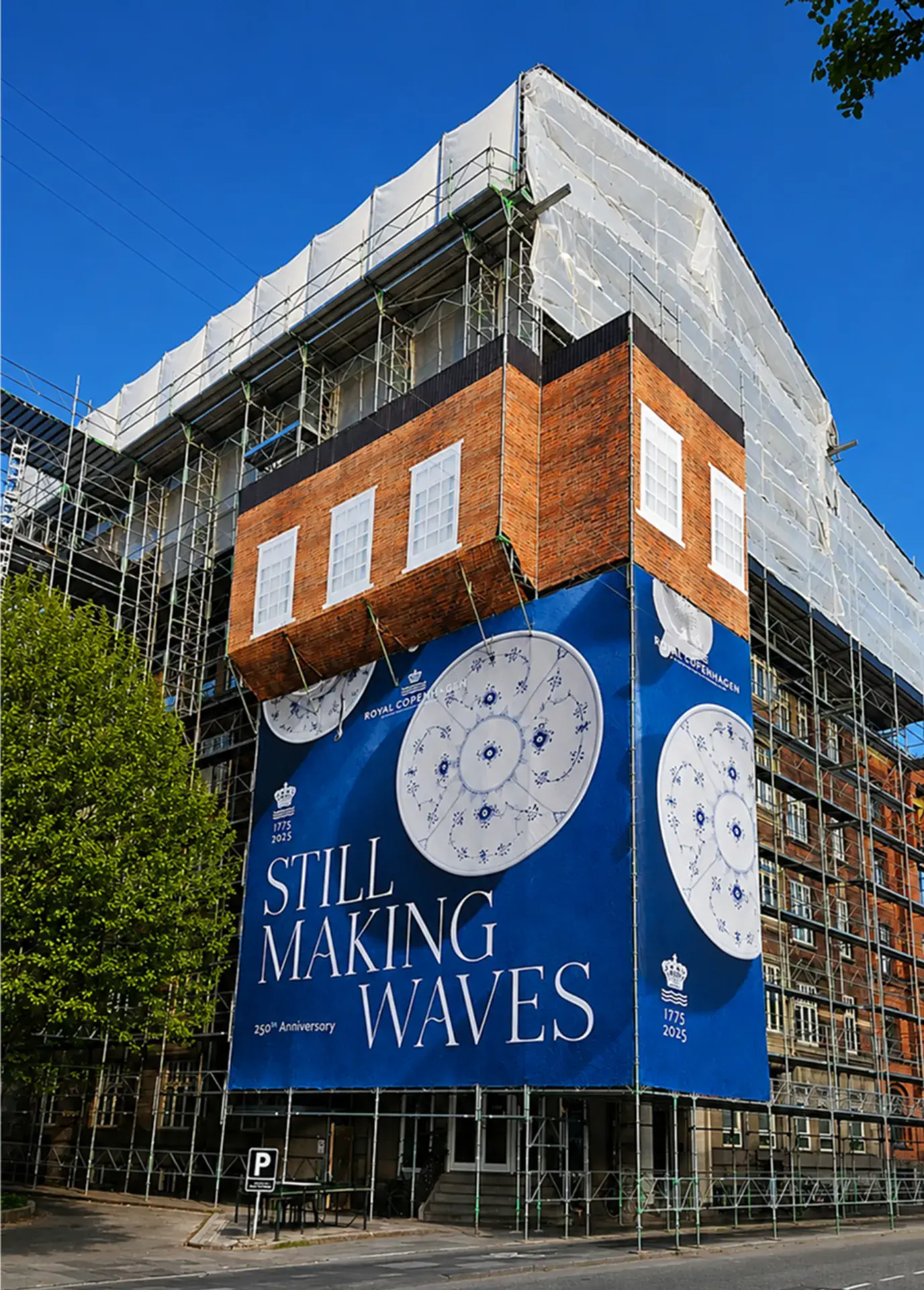 Bygningsarbejde med stillads og banner for Still Making Waves.